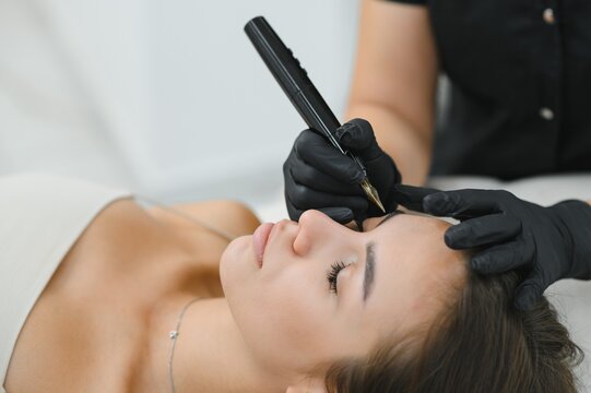 hands of the master who performs the procedure of permanent makeup of eyebrows. Permanent eyebrow makeup PMU for brunettes