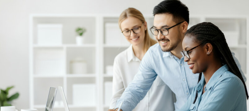 Three people are sitting at a desk with a laptop in front of them