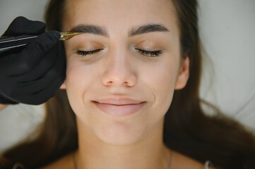 hands of the master who performs the procedure of permanent makeup of eyebrows. Permanent eyebrow...