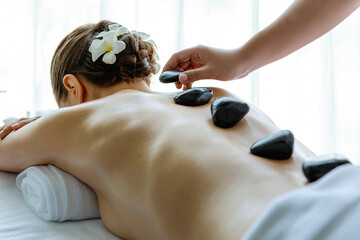 Hot stone massage at spa salon in luxury resort with day light serenity ambient, blissful woman...
