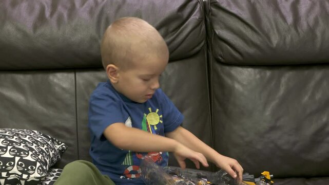 Child unpacking box with robot transformer toy. Face of concentrated little boy taking new toy out of package.