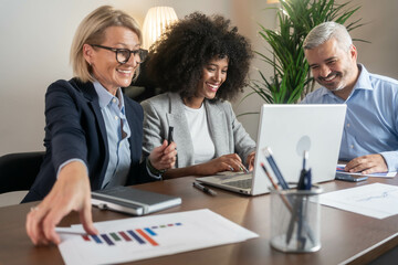 Three busy happy middle aged professional business man and two women executive leaders team using...