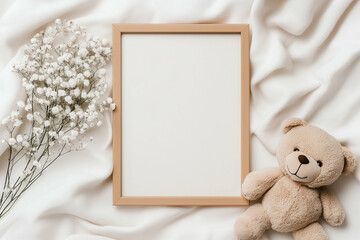 Teddy bear and photo frame with white flowers on white fabric. Teddy bear sitting next to a wooden frame and flowers on a white background. Top view of a teddy bear frame and flowers
