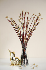 Pussy willow branches in a vase with a golden rabbit figurine