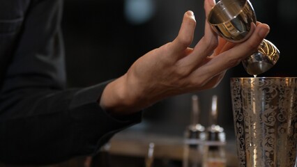Closeup mixing hand bartender holding jigger to measure juice into shaker design preparation for mixed cocktail at bar. Special refresh drink showcasing nightlife mixology inviting at club. Vinosity.