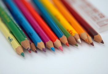  Row of sharpened colored pencils in a spectrum of colors on a white surface