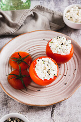 Tomatoes stuffed with cottage cheese and dill on a plate on the table vertical view