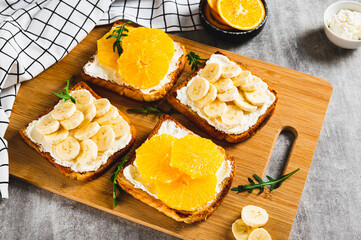 Sandwiches with ricotta, orange and banana on a board on a table