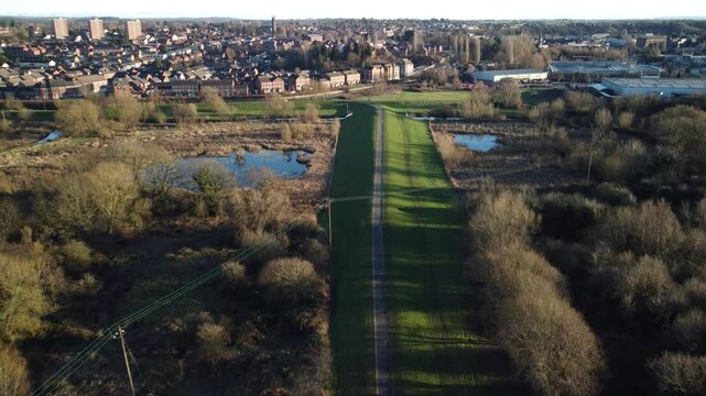 view of rural land with road, leafless trees and puddles near the skyline of Kidderminster Town