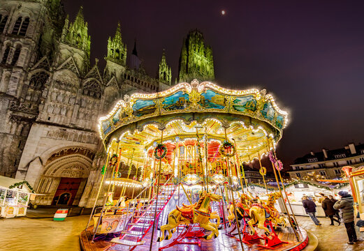ROUEN, NORMANDY, FRANCE - 2025: carousel at Christmas Market, chalets with delicatessen shops, illuminated Notre Dame Cathedral, cobbled pedestrian street in historic center