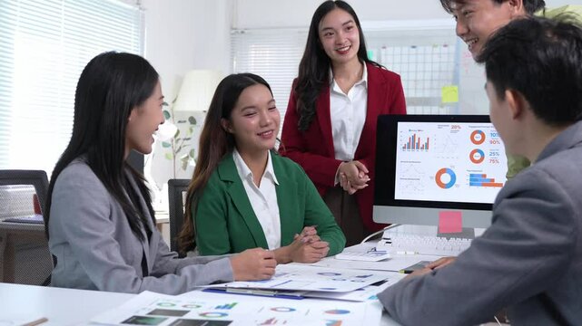 Successful Asian business professionals closing strategic partnership, celebrating collaborative achievement with enthusiastic handshake and clapping in modern corporate meeting room