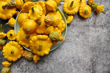 Yellow patisson, pattypan scallop squash vegetable on blue plate on white marble table background....