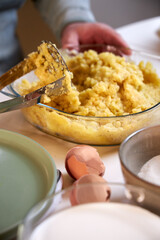 man crushes boiled potatoes for mashed potatoes