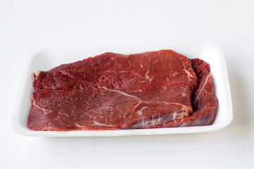 Uncooked beef fillet, on a foam plate on a white surface with copy space