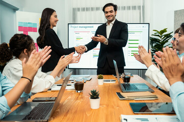 Cheerful meeting room, businesspeople celebrate with handshaking. Successful project was completed before the deadline. Business partnership and collaboration in project management. Habiliment