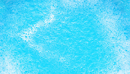 Small foam bubbles in blue water. Abstract white soap foam texture. Concept of cleaning and washing.