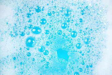 Small foam bubbles in blue water. Abstract white soap foam or soap suds texture. Concept of...