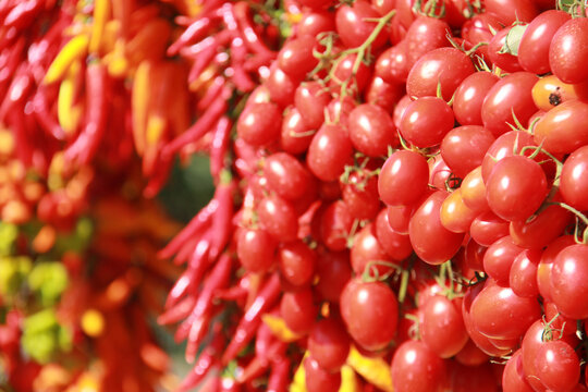 bunches of fresh, bright-coloured red tomatoes and red and yellow peppers, on a market stall in Naples, Italy - Powered by Adobe