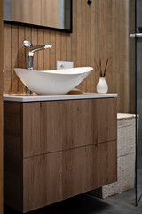 Modern bathroom interior with sink.  Interior of small bathroom in brown color and wooden decor. Ceramic washbasin on cabinet. Scandinavian and vitage style.