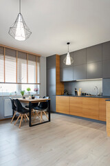 Modern interior of living room with kitchen and dining table with chair. Wooden furniture and floor at design home. Contemporary room with comfortable sofa in new apartment. Vertical.