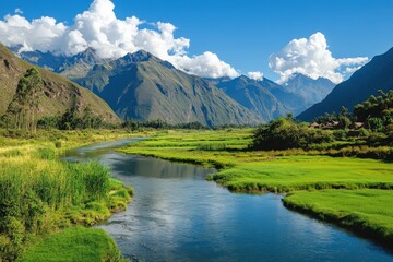 Fototapeta premium Breathtaking view of a river winding through green fields in the Peruvian Andes, surrounded by majestic mountains and blue skies
