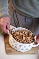fried mushrooms with onions lying in an enameled white pot, close-up view from above