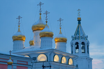 The church is lit up at night, with a large bell tower in the background.