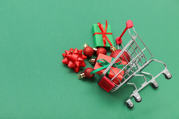 Small shopping cart with Christmas decor on green background