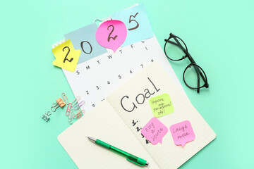 Notebook with to do list, sticky notes and calendar on cyan background. New year goals concept