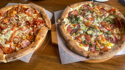 two pizzas with different fillings on a wooden base