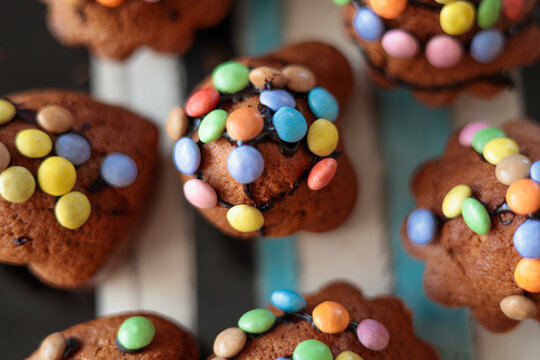 Easter muffins decorated with frosting and colorful bonbons on a striped plate