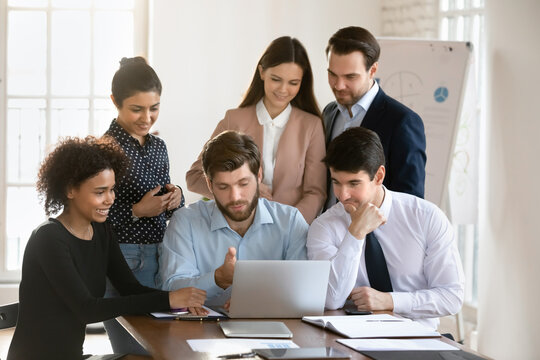 Group of people gathered around laptop engaged in discussion, review new corporate program, working on joint task, share solutions, listen team leader speech explaining strategy, results of research
