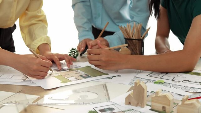 Smart architect and safety engineer discussion about building blueprint on table with architectural document, measurement tools and wooden block scatter around at modern office. Closeup. Delineation.