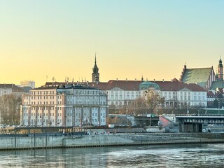 Obraz premium view of a bank of the vistula in the city of warsaw with a bridge and buildings at sunset 
