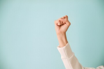 International Women's Day 2025: Accelerate Action. Woman hand gesture signifying achievement of gender equality and empowerment. Female hand with clenched fist on blue color background