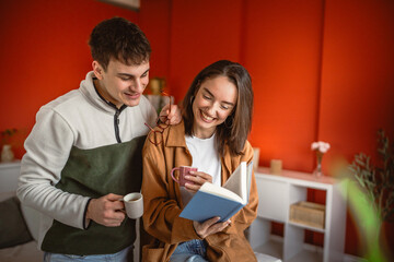 young couple drink coffee and read book together in modern living room