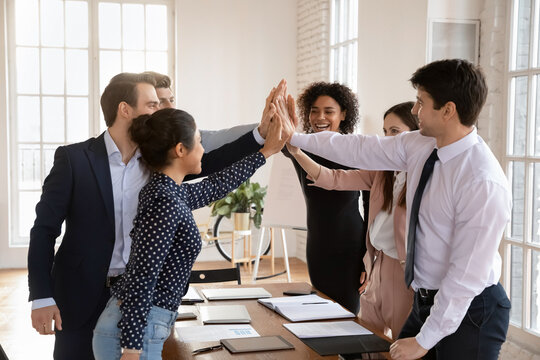 Multiethnic workmates giving each other high-fives, gesture of teamwork, collective achievement, celebrate reaching corporate goal, acknowledge, successful collaboration, express mutual encouragement