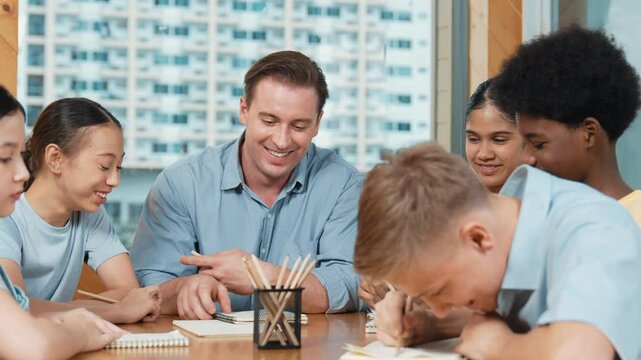 Smart high school boy in casual shirt asking professional teacher while student with mixed races writing book. Caucasian instructor giving comment while creative child pointing at note. Edification