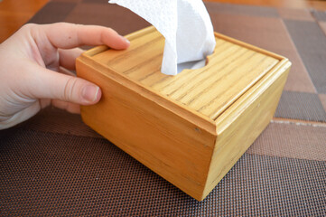 hand holding a wooden tissue box with a white tissue protruding from the top home interior design...