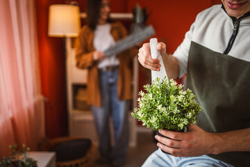 young man gardener use spray for hydration home plant