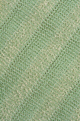 A detailed close-up shot of the woven texture of a light green back scrubber, highlighting its intricate pattern