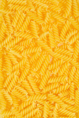 A close-up, top-down shot of uncooked fusilli pasta, showcasing its spiral shape and golden color