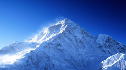 A towering snow-covered mountain peak rises against a deep blue sky as wisps of windblown snow create a dramatic high-altitude atmosphere