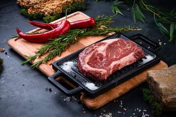raw steak meat with pepper, salt and rosemary is prepared for grilling