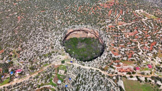 Aerial view capturing limestone landscape with deep, massive cennet and cehennem sinkholes dominating rugged terrain of remote mersin province