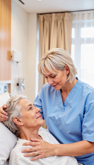 Caring nurse comforting elderly patient in hospital bed.
