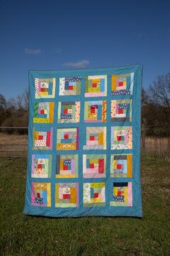 colorful log cabin quilt against blue sky