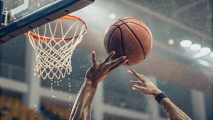 A basketball player's hands reach for the hoop, a moment of intense focus and athleticism.The ball soars through the air, a testament to the player's skill and precision.