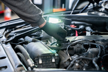 Serviceman checks the oil level in a car engine