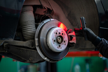Serviceman checks the brake discs of a car